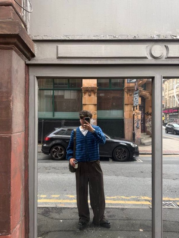 Sebastian filming in a shop window reflection